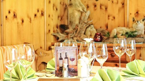 Ein stilvoll gedeckter Tisch mit Weingläsern und liebevollen Details sorgt für ein gemütliches Ambiente im rustikalen Restaurant