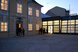 Historisches Gebäude mit beleuchteten Fenstern und modernem Glasbau in einem Innenhof bei Abenddämmerung