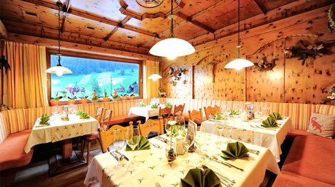 Eine gemütliche, rustikale Gaststube mit viel Holz und festlich gedeckten Tischen lädt zum Genießen und Verweilen ein