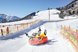 Menschen rodeln fröhlich im verschneiten Skigebiet