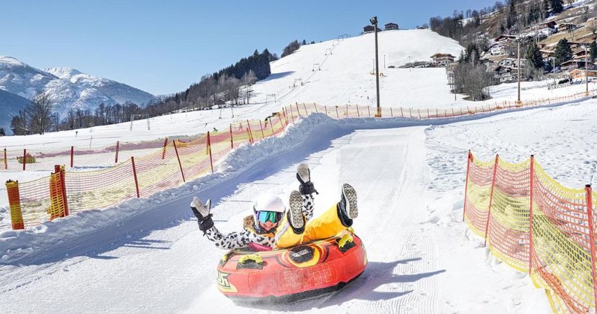 Menschen rodeln fröhlich im verschneiten Skigebiet