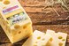 Käselaib mit typischen Löchern und zwei angeschnittenen Käsescheiben auf einem rustikalen Holztisch