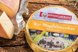 Runder Bio-Magdalenenkäse mit Produktetikett sowie angeschnittenem Käselaib auf einem rustikalen Holztisch präsentiert