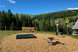 Spielbereich mit Balanciergeräten und Spielstationen auf einer großzügigen Wiese vor einer idyllischen Berglandschaft