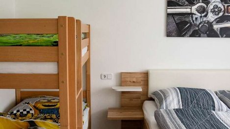 Gemütliches Schlafzimmer mit Doppelbett, Stockbett und heller, freundlicher Einrichtung aus Holz