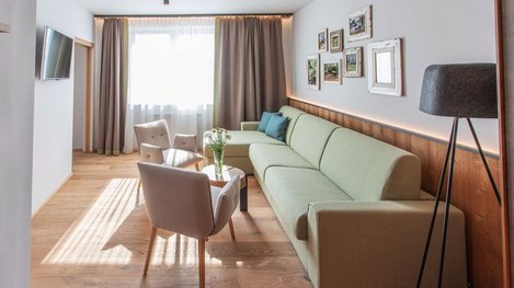 Helles Wohnzimmer mit Sofa, Sesseln und großer Fensterfront