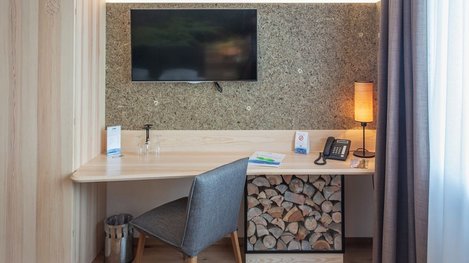 Schreibtisch mit Sessel und Fernseher in einem modern eingerichteten Hotelzimmer