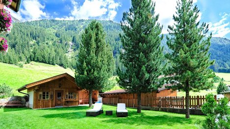 Ein gepflegter Garten mit Holzhütte und Liegewiese bietet Erholung inmitten einer idyllischen Berglandschaft
