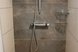 Moderne, ebenerdige Dusche mit Regendusche, eleganten Fliesen und zeitgemäßer Ausstattung