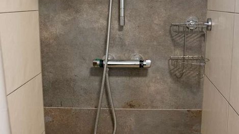 Moderne, ebenerdige Dusche mit Regendusche, eleganten Fliesen und zeitgemäßer Ausstattung