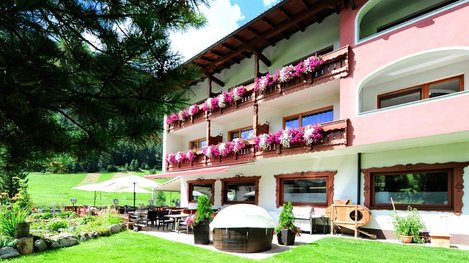 Ein gepflegtes Hotel mit blumengeschmückten Balkonen liegt in ruhiger, grüner Umgebung