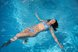 Eine Frau schwimmt entspannt in einem strahlend blauen Schwimmbecken