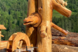 geschnitzte Holzfigur mit einem Bärenmotiv vor einer bewaldeten Bergkulisse