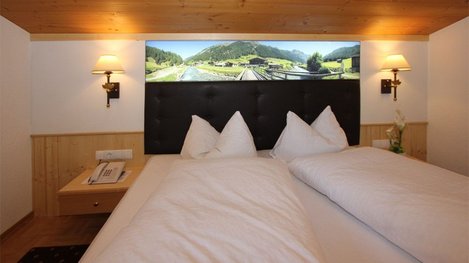 Ein gemütliches Doppelzimmer mit großem Bett und warmem Holzambiente lädt zum Entspannen und Wohlfühlen ein