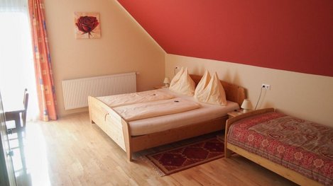 Gemütliches Gästezimmer mit Doppelbett und Einzelbett, freundlicher Farbgestaltung sowie behaglicher Wohlfühlatmosphäre
