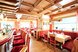 Ein gemütliches Restaurant mit traditionellen Holzmöbeln und heller, einladender Atmosphäre lädt zum Verweilen ein