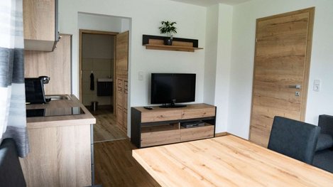 Modern eingerichteter Wohn- und Essbereich mit offener Küche, Holzmöbeln und gemütlicher Atmosphäre
