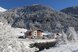 Ein Hotel inmitten einer verschneiten Winterlandschaft, umgeben von schneebedeckten Bergen und frostigen Bäumen