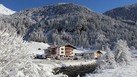 Ein Hotel inmitten einer verschneiten Winterlandschaft, umgeben von schneebedeckten Bergen und frostigen Bäumen