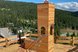 Holzaussichtsturm mit Kletternetz und Aussichtsplattform vor einer beeindruckenden Berglandschaft