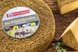Runder Bio-Käse mit Kräuterkruste und angeschnittenem Käsestück auf einem rustikalen Holztisch präsentiert