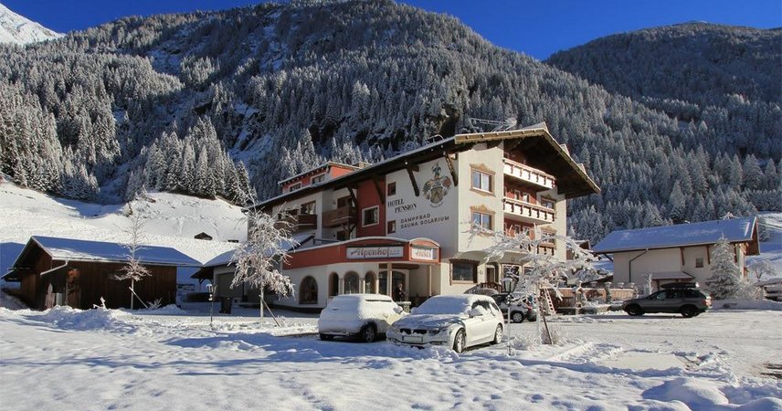 Ein Hotel in winterlicher Berglandschaft, umgeben von schneebedeckten Wiesen und Bergen