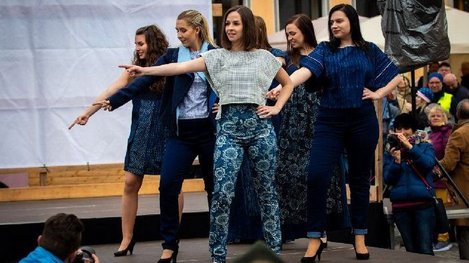 Eine Modenschau präsentiert moderne Kleidung mit traditionellen Blaudruckmustern auf einer Bühne vor Publikum