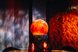 Eine leuchtende orangefarbene Kugel steht vor einer Wand mit feurigen Lichtmustern