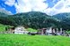 Ein idyllisches Alpenhotel liegt auf einer grünen Wiese vor einer beeindruckenden Bergkulisse
