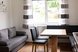 Heller und gemütlicher Wohnbereich mit Sofa, Esstisch und großen Fenstern für eine freundliche Atmosphäre