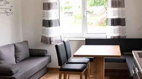 Heller und gemütlicher Wohnbereich mit Sofa, Esstisch und großen Fenstern für eine freundliche Atmosphäre
