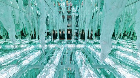 Spiegelnder, türkisfarbener Kunstraum mit reflektierenden Glasflächen und zahlreichen hängenden, eisartigen Glaselementen