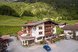 Ein gemütliches Hotel liegt eingebettet in einer grünen Berglandschaft mit Wiesen und Wäldern