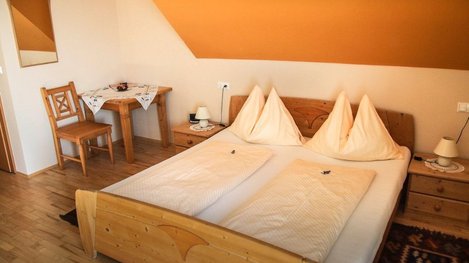 Helles und gemütliches Doppelzimmer mit komfortablem Bett, liebevollen Holzmöbeln und einladender Wohlfühlatmosphäre