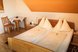 Helles und gemütliches Doppelzimmer mit komfortablem Bett, liebevollen Holzmöbeln und einladender Wohlfühlatmosphäre