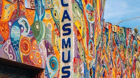 Farbenfroher Gebäudeturm mit dem Schriftzug „GLASMUSEUM“ und einer kunstvoll gestalteten Fassade aus bunten, abstrakten Mustern
