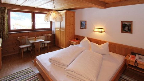 Ein gemütliches Doppelzimmer mit viel Holz, großem Bett und heller, behaglicher Atmosphäre lädt zum Entspannen ein
