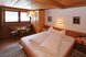 Ein gemütliches Doppelzimmer mit viel Holz, großem Bett und heller, behaglicher Atmosphäre lädt zum Entspannen ein