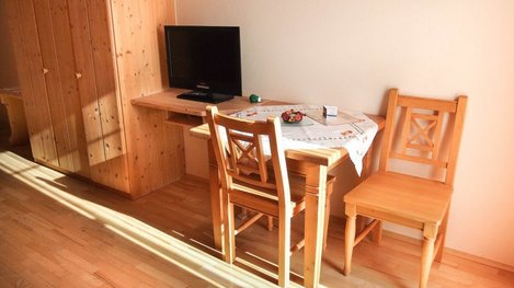 Gemütliche Sitzecke mit Esstisch, TV und rustikalen Holzmöbeln in wohnlicher Atmosphäre