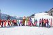 Eine große Gruppe bunter Skifahrer posiert auf einer verschneiten Piste