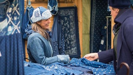 Ein Marktstand präsentiert traditionelle Blaudruck-Textilien in verschiedenen Blautönen und lädt zum Stöbern in regionalem Handwerk ein
