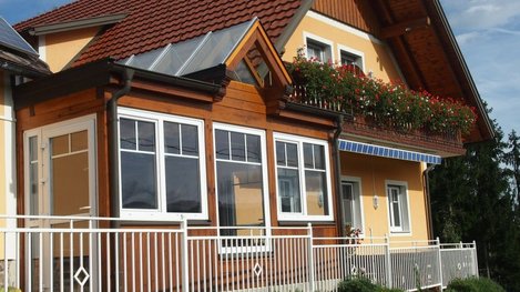 Einladendes Gästehaus mit gepflegter Fassade, verglastem Wintergarten und blumengeschmückten Balkonen in ruhiger Lage