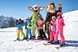 Eine Gruppe Skifahrer posiert mit zwei Maskottchen im Schnee