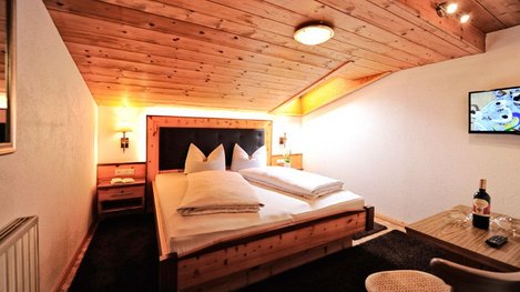 Ein gemütliches Zimmer im alpinen Stil mit Holzmöbeln und komfortablem Doppelbett lädt zum Entspannen und Wohlfühlen ein